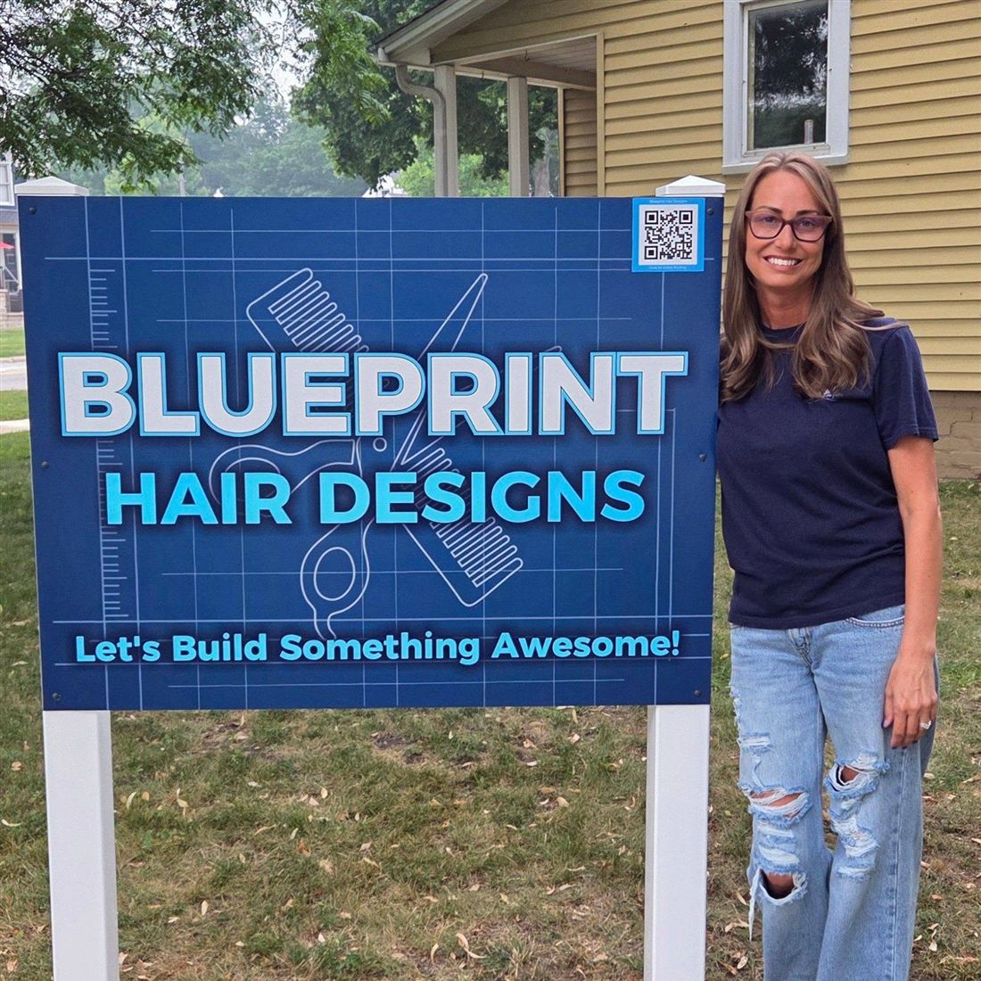 April Pengelly standing beside the Blueprint Hair Designs sign outside the studio