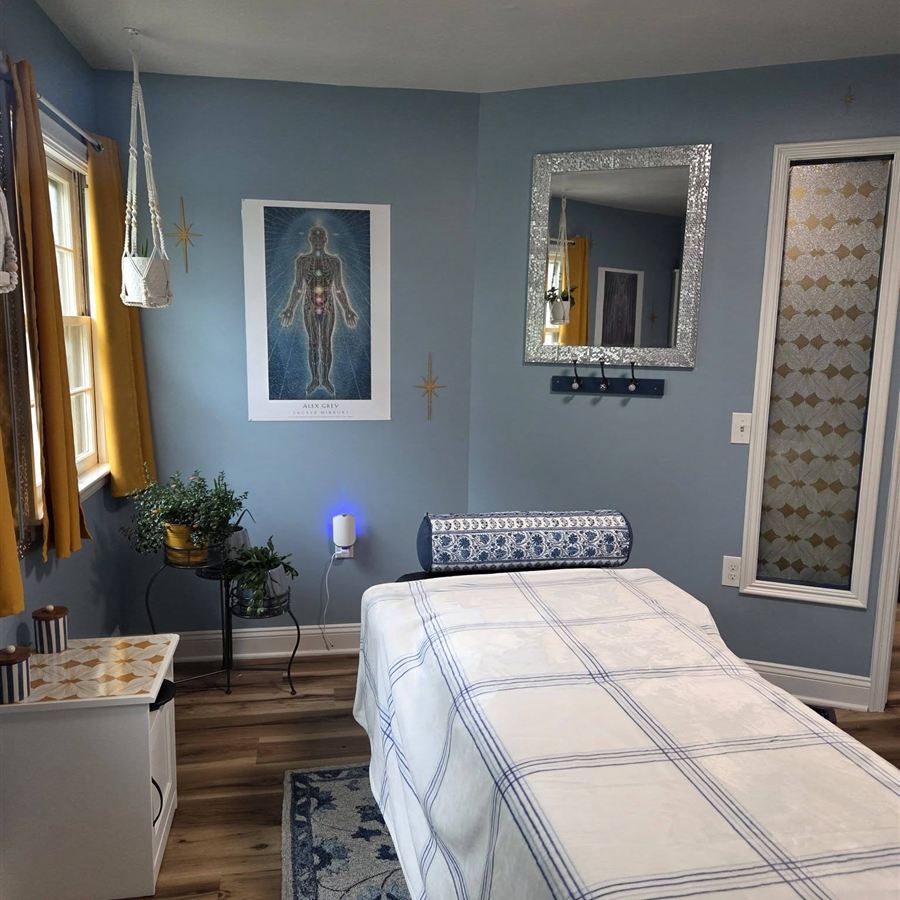The massage room at Blueprint: a table, soft blue walls, plants, and warm light